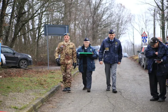 Militari e soci portano il tricolore piegato verso il monumento